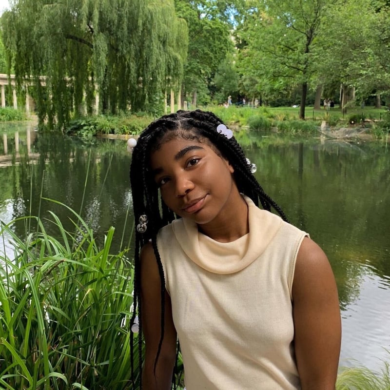 Assistant editor Bryn Evans, sitting among grasses in front of a pond. 