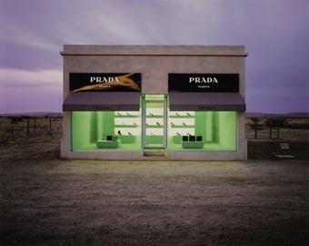 a prada store in the middle of the Texas desert at twilight, the shop windows show high heeled shoes and purses with a green glow painting the interior with a alien light