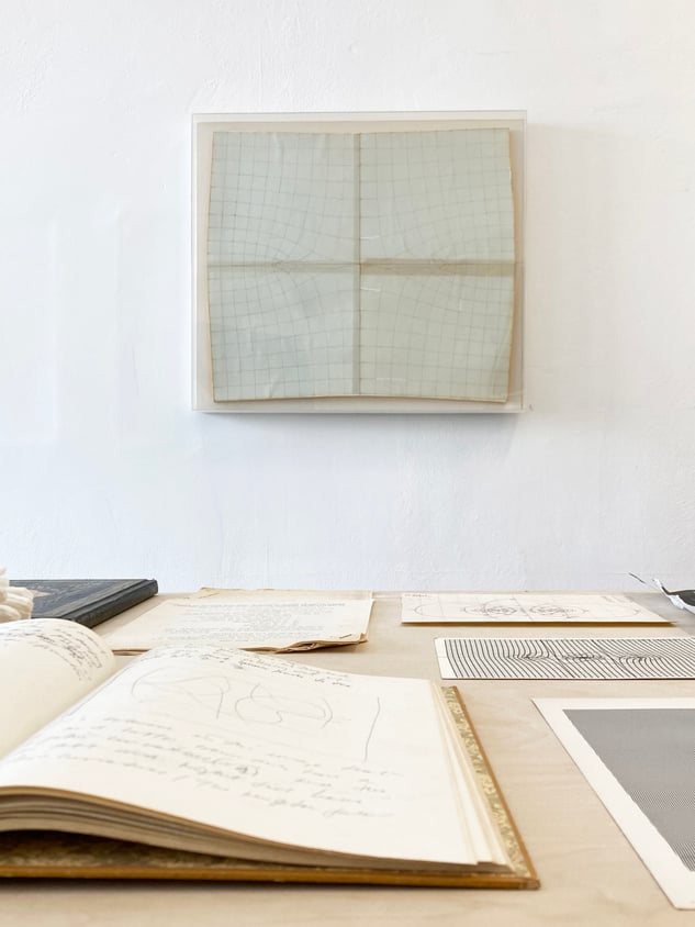 installation view white wall notebooks in foreground with architectural drawings