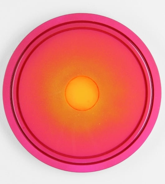 a large reddish circular painting with reverberating shades of pink, orange, and gold, like a sunset from a birds-eye view