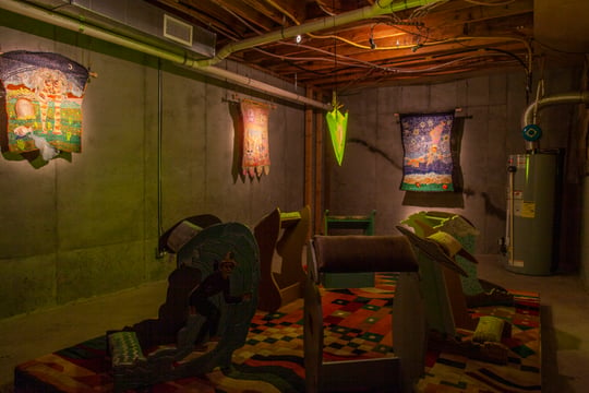 installation view of dimly lit exhibition with sculptures and wall hangings