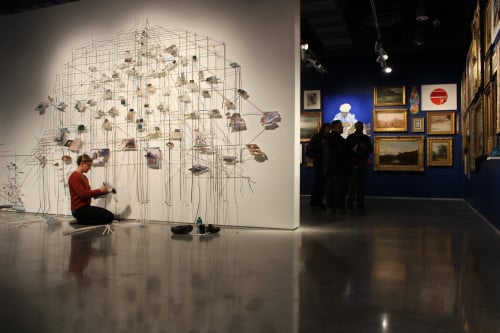 Adriane Colburn installing Denatured Ground, 2012; ink jet prints, ink, acrylic, postcards, Mylar, “See Through Walls” exhibition, Zuckerman Museum of Art.