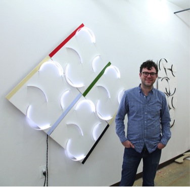JD Walsh in his studio with (l to r) Phased Arcs, 2013, acrylic on MDF, Plexiglas, LED lights, micro controller; and 8/8, 2014, Hydrocal, wood, acrylic sheet.