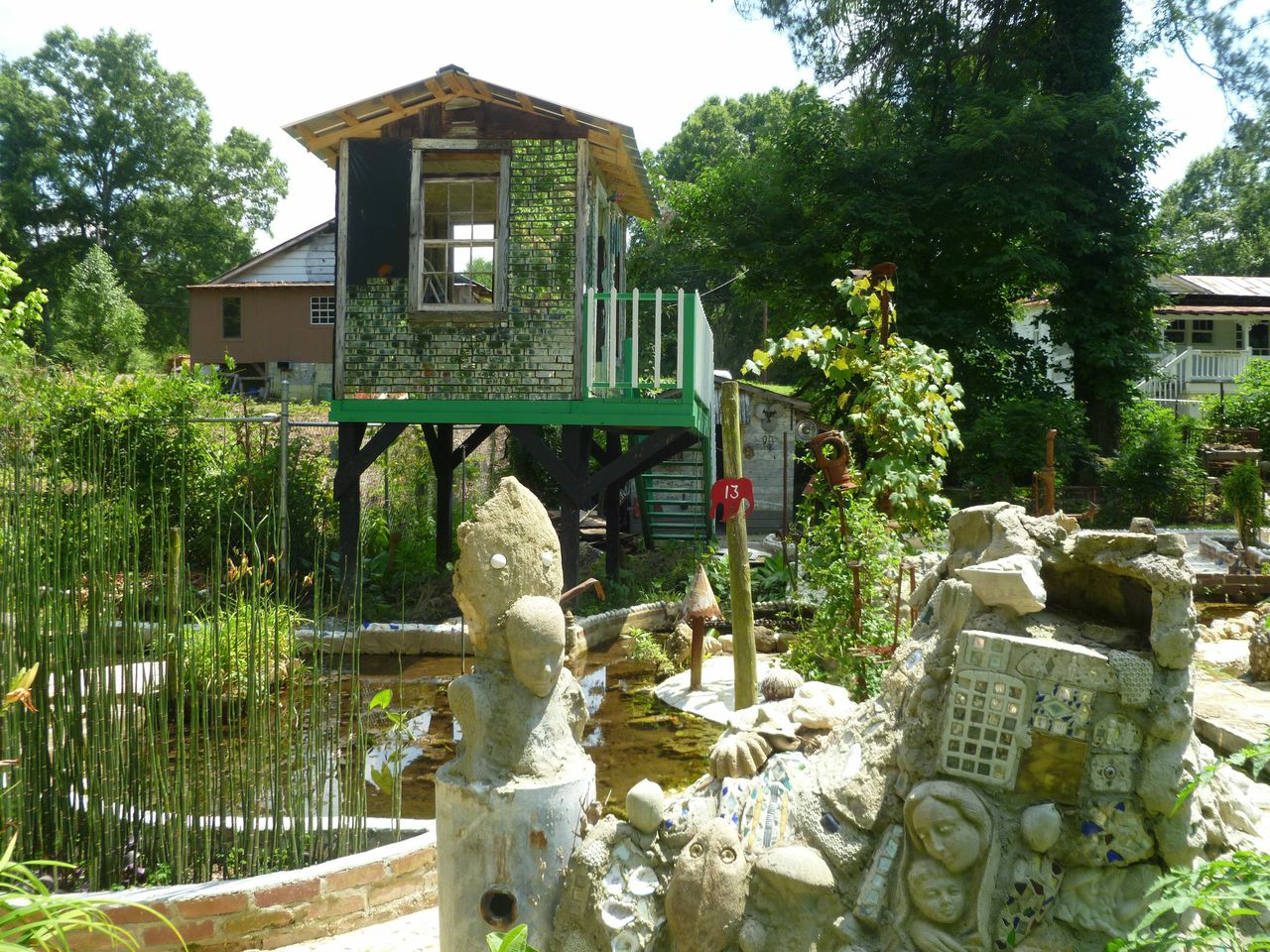 Sunny view of Howard Finster's Paradise garden filled with green trees and wild sculptures