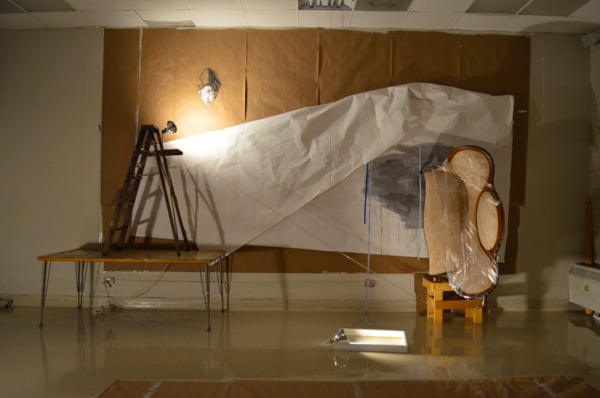 an installation featuring yellow couch with plastic wrap in a dimly lit room