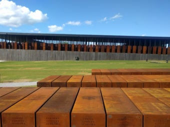 Rusted sculptural blocks, part of Nkyinkyim, a piece by Kwame Akoto-Bamfo in a green outdoor space