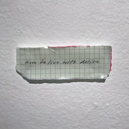 An image showing a scrap of graph paper containing the handwritten text, "how to live with desire."