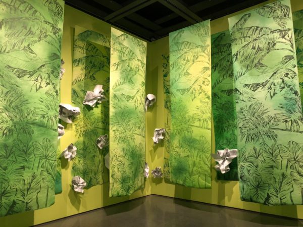 Vertical banners printed with foliage suspended from the ceiling with large paper wads hanging among them.