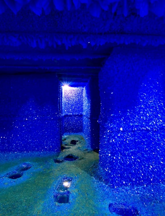 an interior room with deep blue crystals growing on the walls, floor and ceiling.