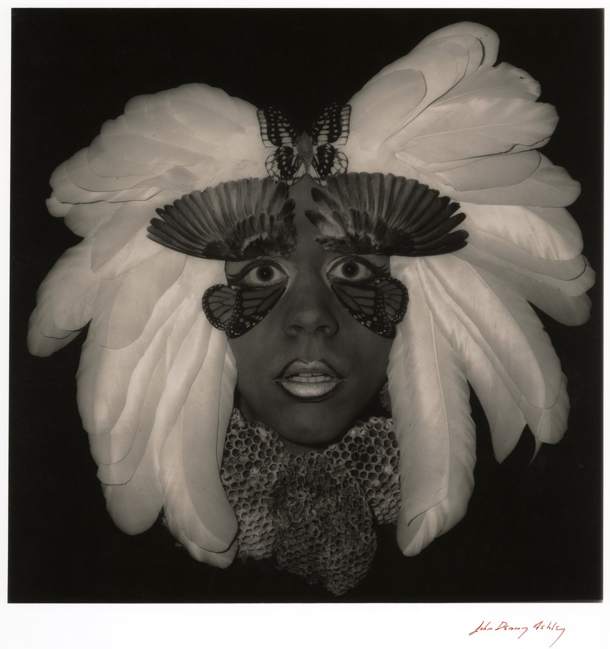 black and white head shot of a man wearing elaborate makeup and a feather headdress