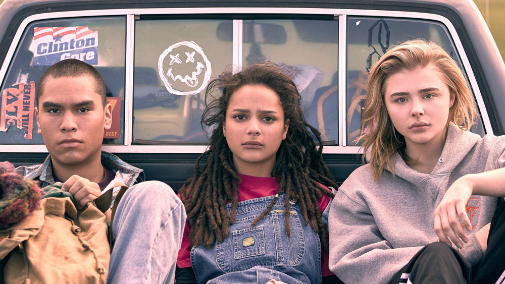 A teen boy and two teen girls sitting in the back of a pickup truck. 