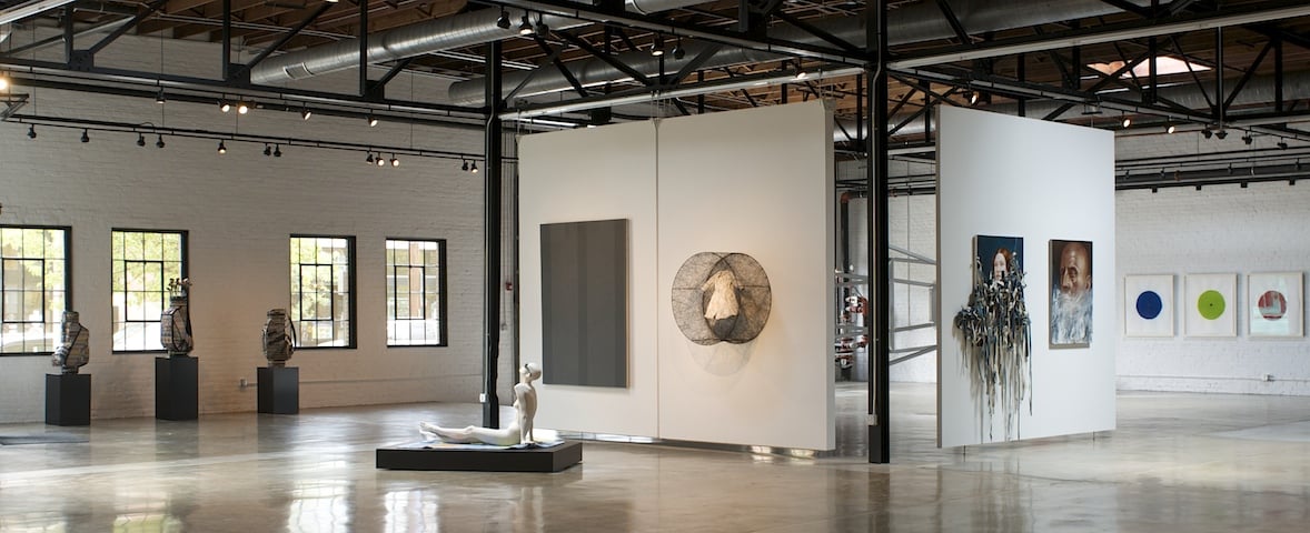 Cavernous space with freestanding walls and art on the walls and sculptures on the floor.