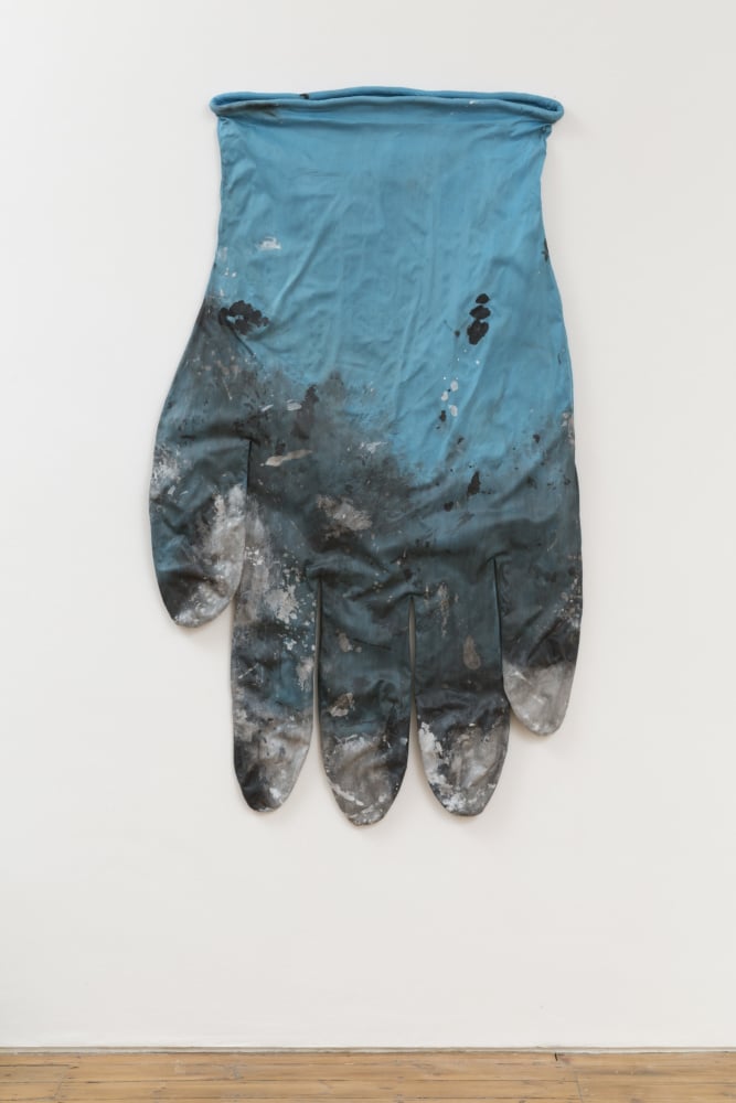 an oversized blue latex medical glove with paint. 