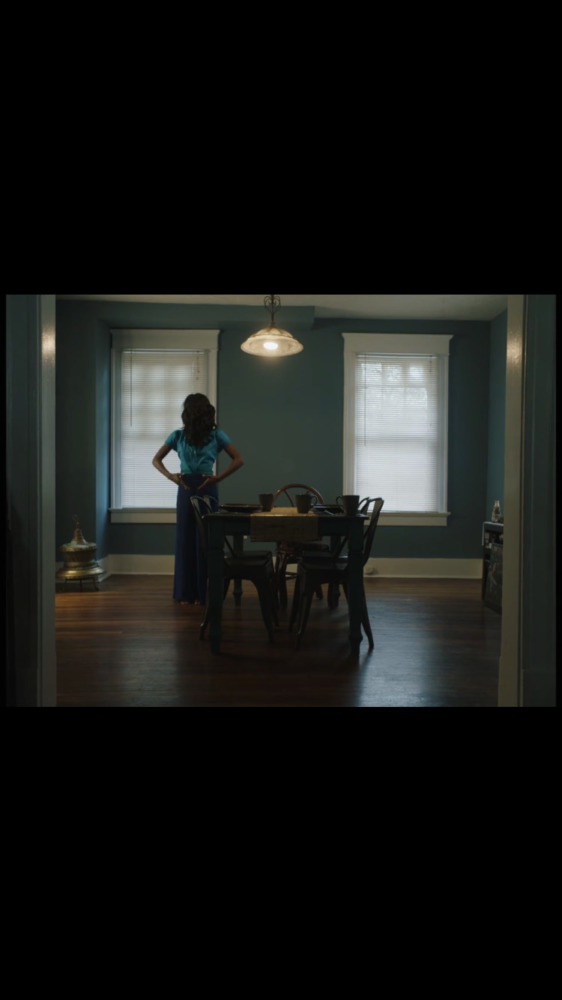 a film still of a woman at a table