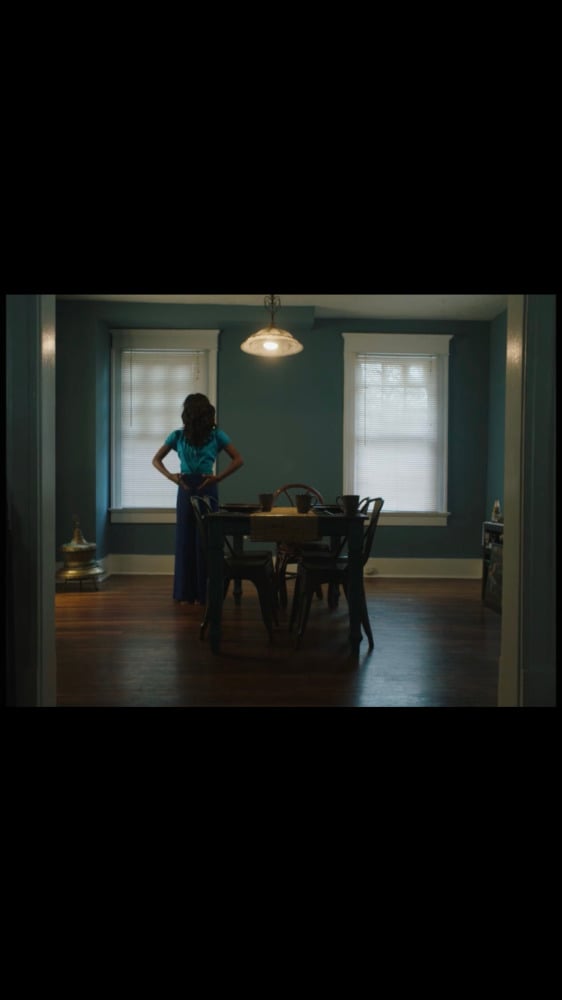 a film still of a woman at a table