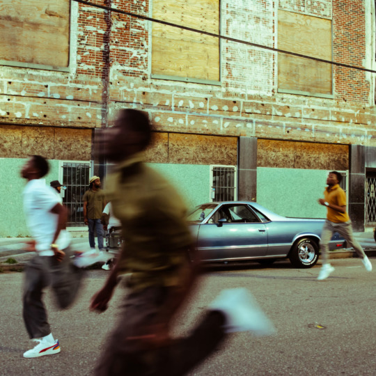 Black children running down a street, blurred slow-capture photograph