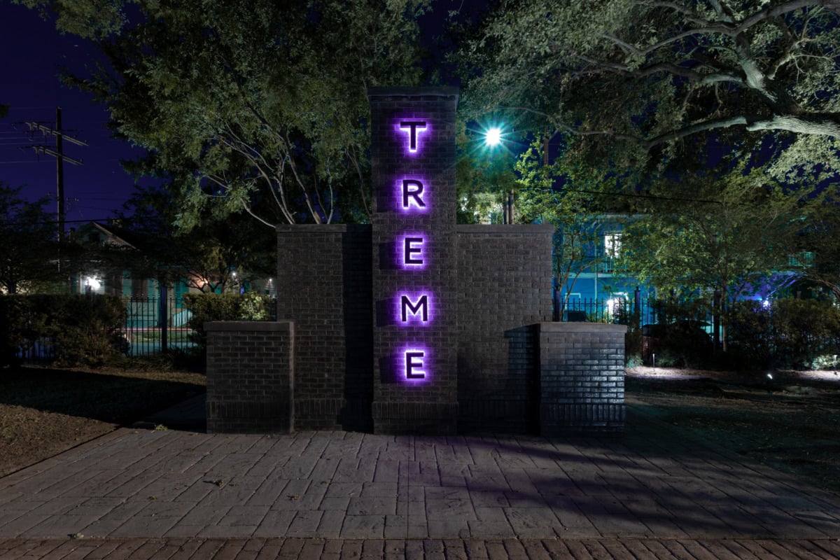 a large brick structure with black letters illuminated by purple light that reads TREME.