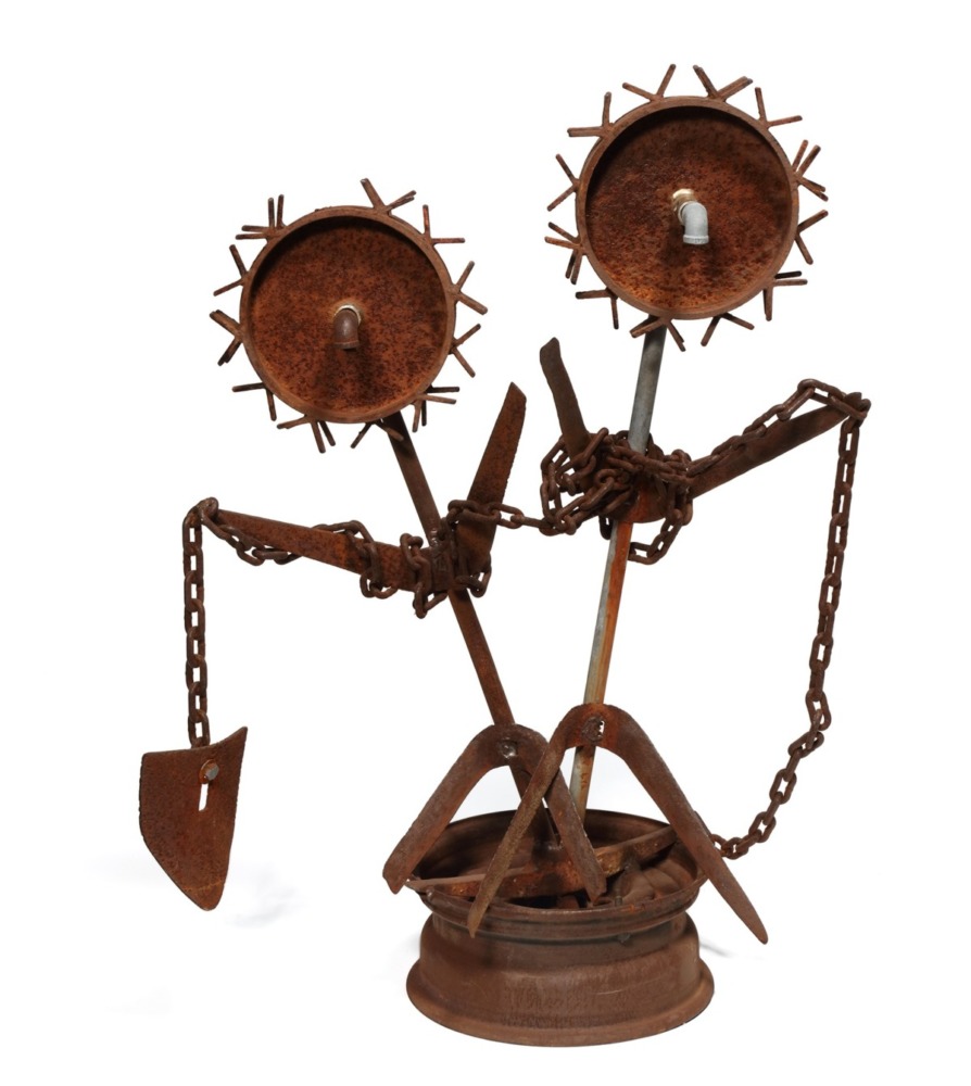 rusted metal sculpture of two gears wrapped in chains on a rusted pedestal