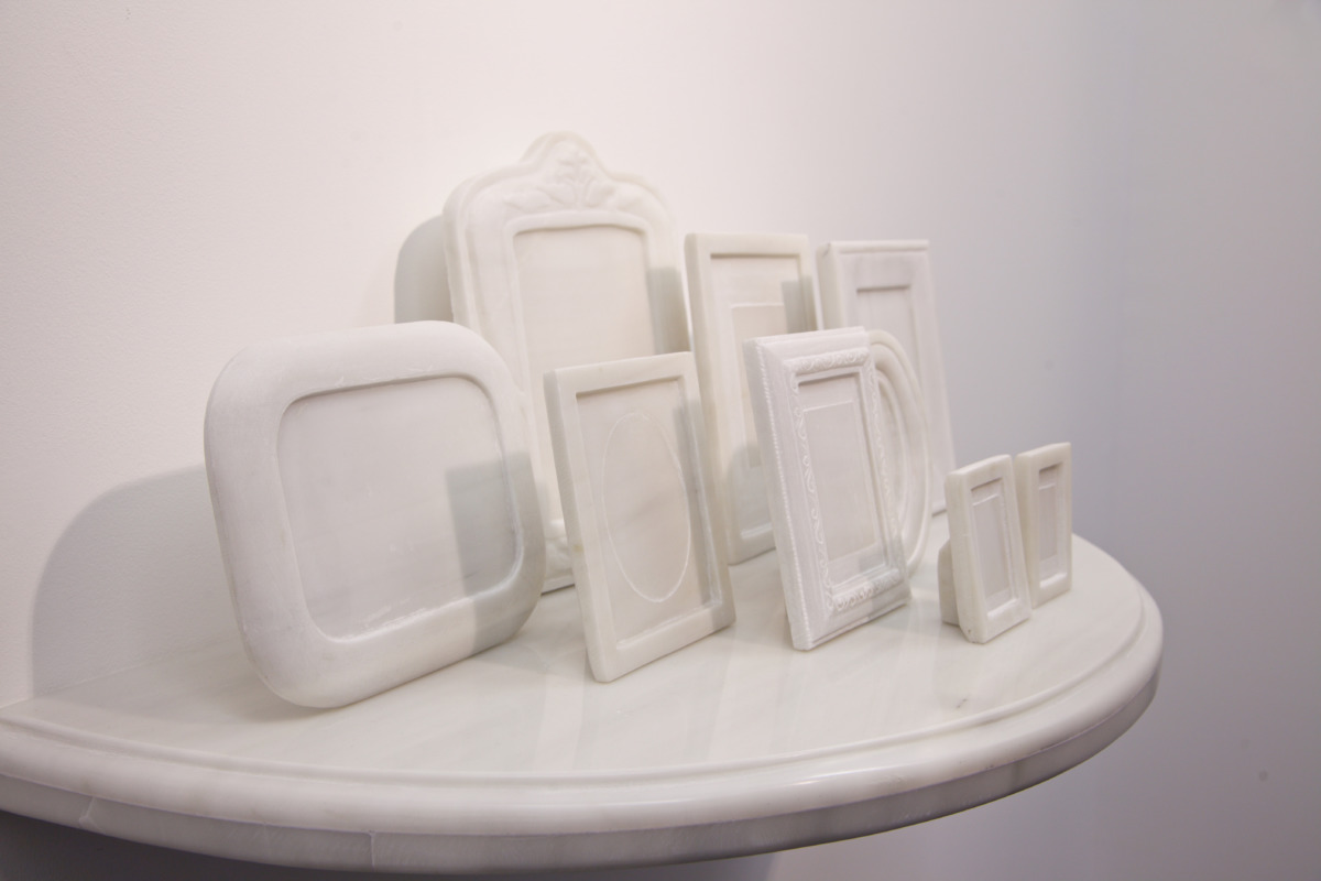 eight empty picture frames carved of white marble sit on a white marble table