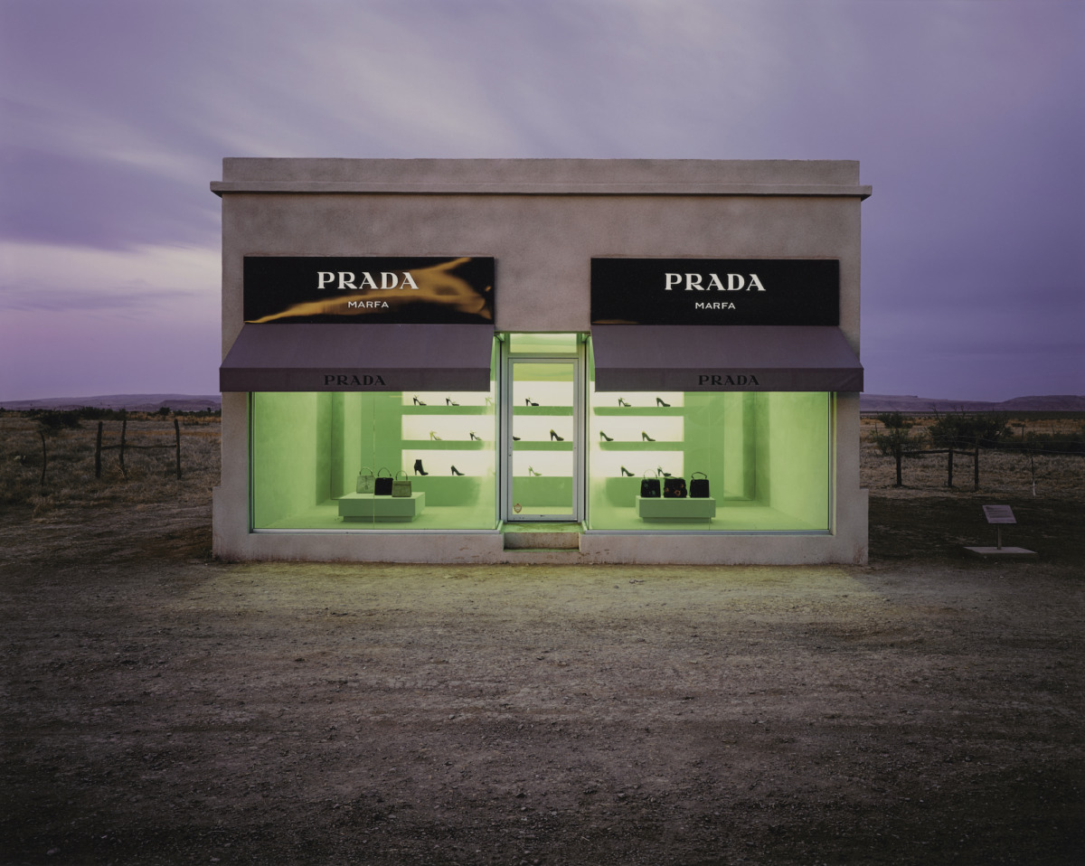 a prada store in the middle of the Texas desert at twilight, the shop windows show high heeled shoes and purses with a green glow painting the interior with a  alien light