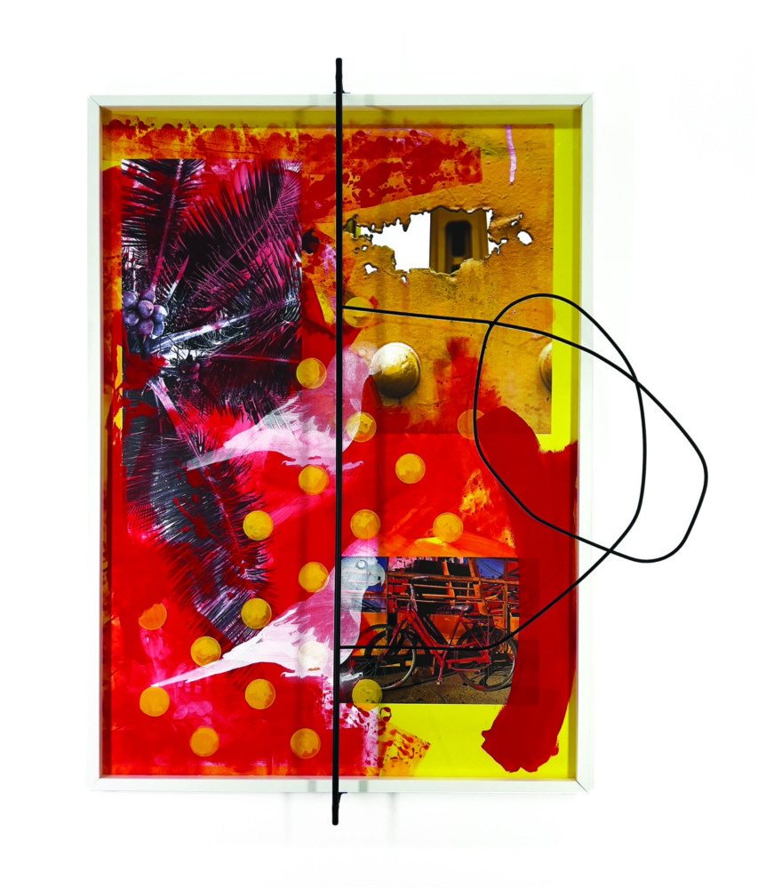 red and yellow splashes of paint with palm tree and bicycle photos  behind glass and a steel rod going down the middle the piece which curls to the right twice
