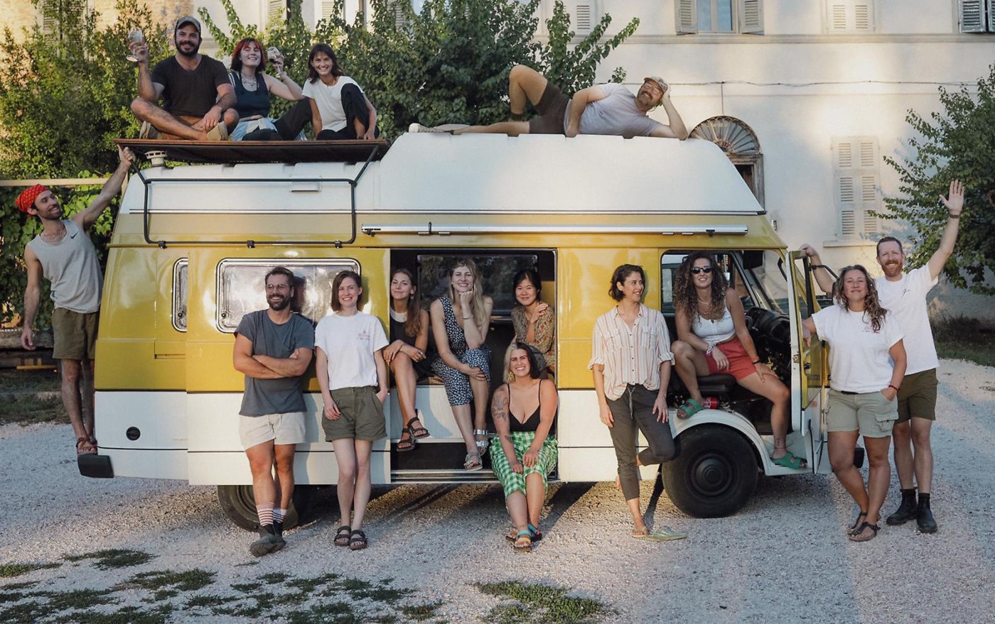 a group of people sit in and around an open van facing the camera