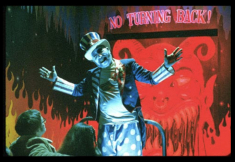 clown figure stands with arms open in front of a horror hause