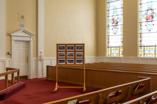 installation view of board with artist work in the middle of a church