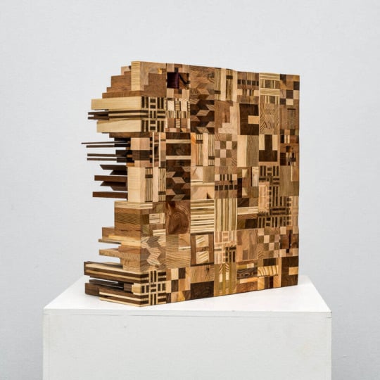 installation view of wood collaged sculpture on white pedastal