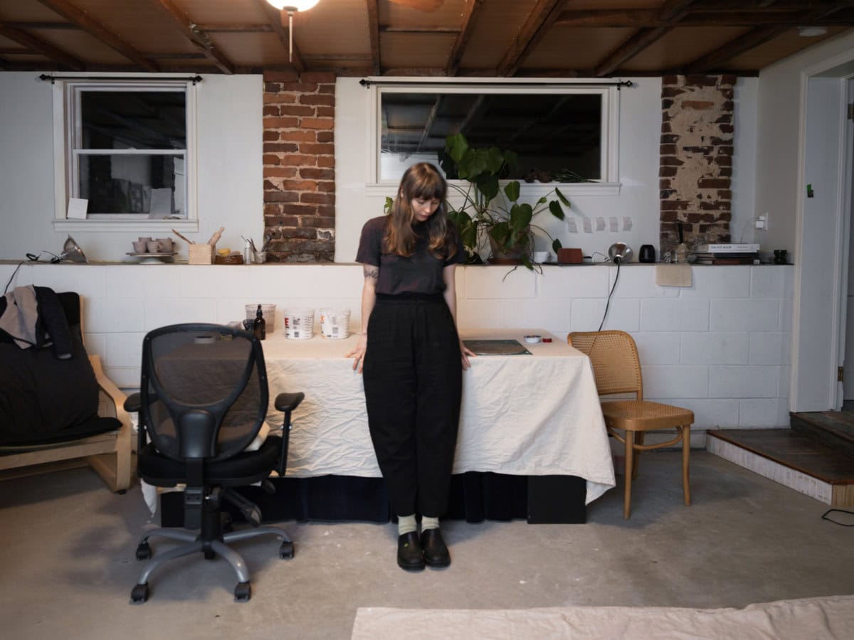 image of woman standing against desk in their studio
