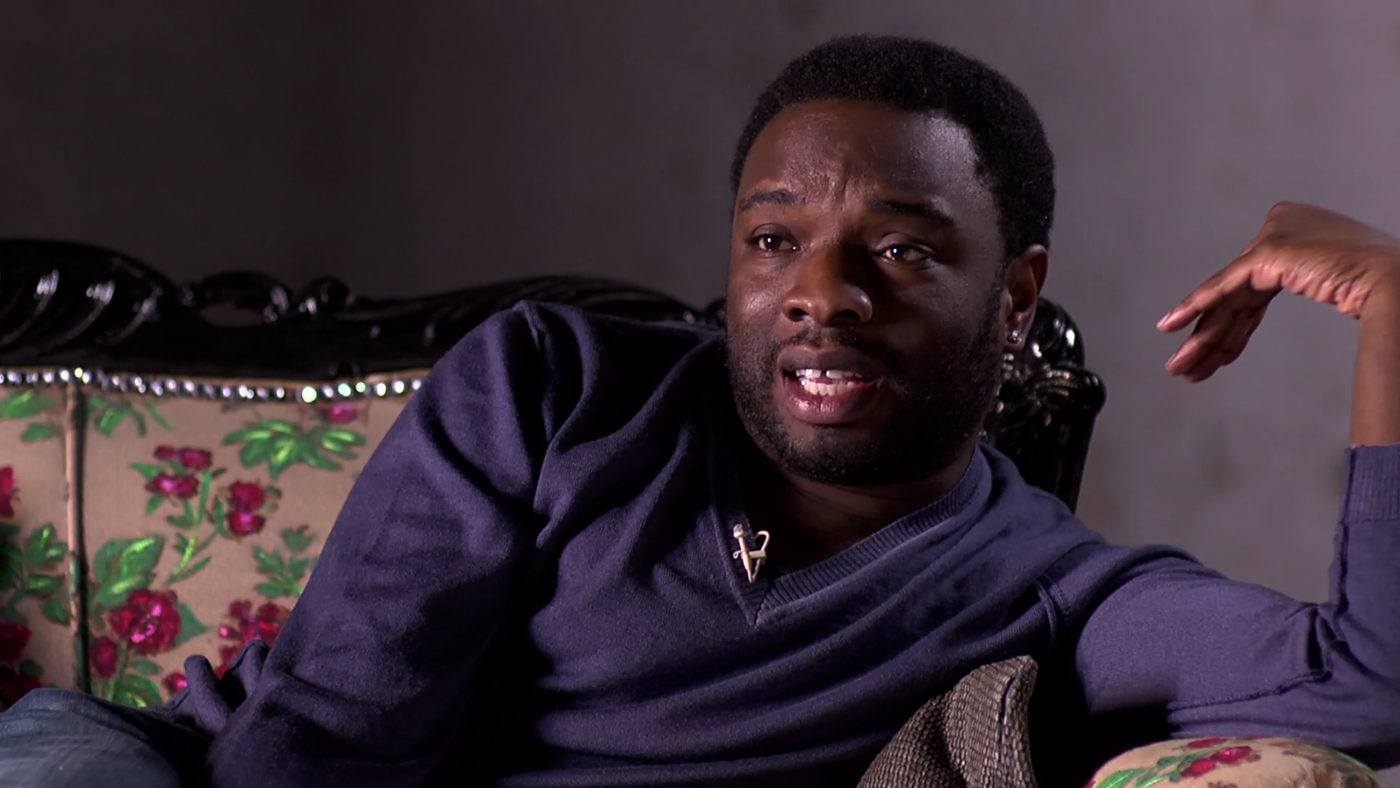 video still of black man sitting on couch