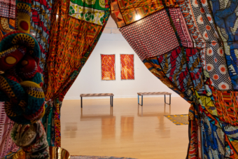 The view from inside Njeri Kinuthia's "Nyumba" (2024) at Gallery221@HCC Dale Mabry. Visible is Njeri Kinuthia's "Still Here | & ||," 2023, bleach and ink on Kenyan fabric, 54 x 34 inches. Image courtesy of HCC Art Galleries, Tampa.